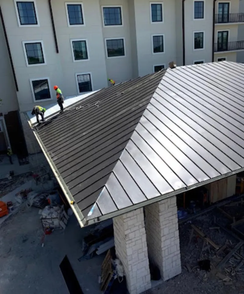 Crew installing standing seam metal roof panels on a commercial project in Salida